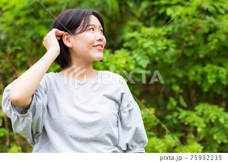 髪を耳にかける10代の女性 自然のイメージの写真素材