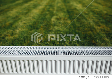 radiator on green lawn, ecological heating concept 75933169