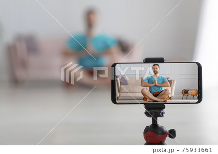 Middle aged man online streaming yoga workout. Live streaming on a smartphone. Focus on smartphone. 75933661