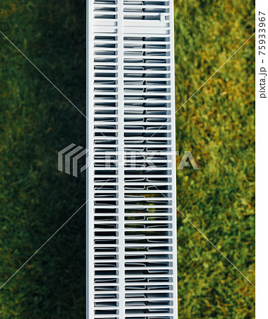 radiator mesh, green lawn background, ecological heating concept 75933967