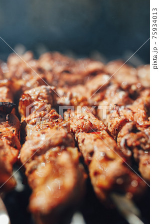 grilled barbecue meat on skewers with smoke 75934013