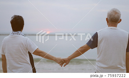 Asian senior elder couple holding hands looking sunset sea ocean together happy retirement life 75937222