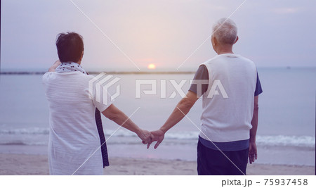 Asian senior elder couple holding hands looking sunset sea ocean together happy retirement life 75937458