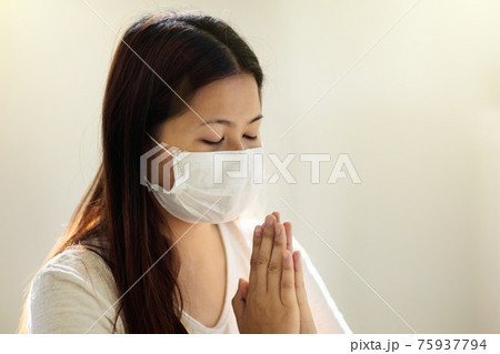 Asian woman in face mask praying for patient Asian woman in face mask praying for patient 75937794
