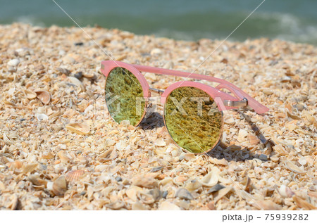 Pink sunglasses against the sun on the beach sand Pink sunglasses against the sun on the beach sand 75939282