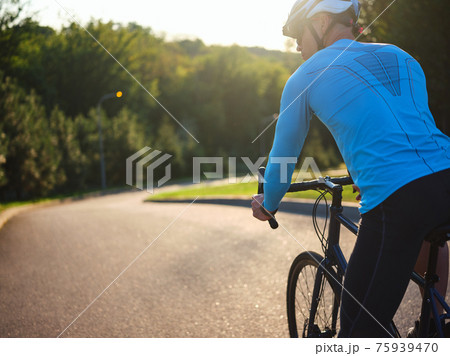 Keep healthy. Rear view of male cyclist on the road. Biker riding a bike in park on a sunny day 75939470