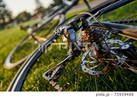 Close up shot of bicycle chain and crank set on profesional black road bike on the grass on a sunny day Close up shot of bicycle chain and crank set on profesional black road bike on the grass on a sunny day 75939488