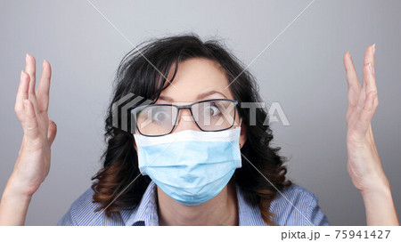 Woman wearing protection face mask against coronavirus and misted glasses. Woman in a mask looking shocked with hands up or worried. Medical mask, Close up shot, Select focus, Prevention from covid19 Woman wearing protection face mask against coronavirus and misted glasses. Woman in a mask looking shocked with hands up or worried. Medical mask, Close up shot, Select focus, Prevention from covid19 75941427