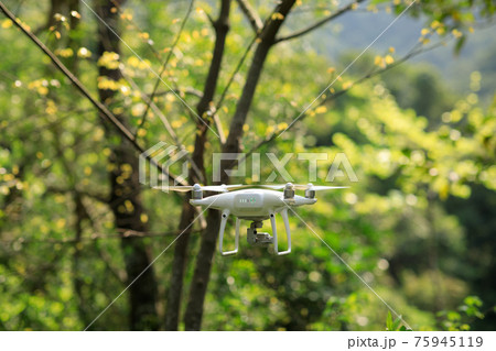 White drone with camera flying in spring tropical forest White drone with camera flying in spring tropical forest 75945119
