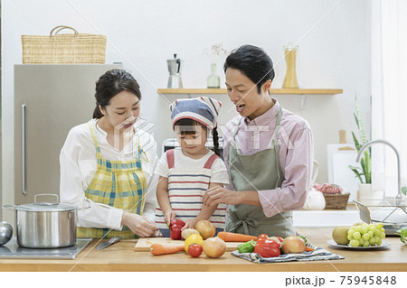 野菜を切る女の子と見守る両親　ファミリー　キッチン　 75945848