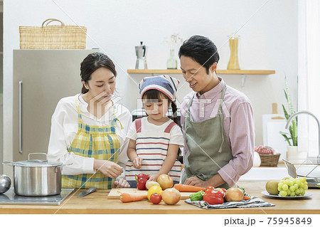 野菜を切る女の子と見守る両親　ファミリー　キッチン　 75945849