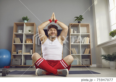 Happy chubby man enjoying meditation and smiling sitting in yoga pose on floor at home 75947077