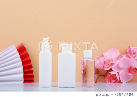 Face cream, cleaning foam and moisturizing or exfoliating lotion against beige background with wavers and flowers 75947484