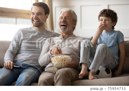 Overjoyed three generations of men watch TV 75954733