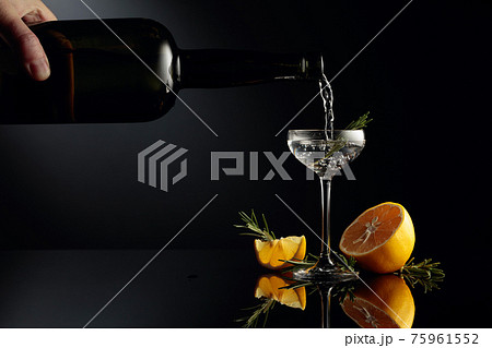Gin with lemon and rosemary on a black reflective background. Gin with lemon and rosemary on a black reflective background. 75961552