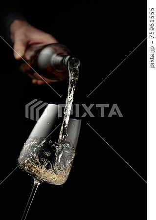 Pouring white wine in a glass goblet. Pouring white wine in a glass goblet. 75961555