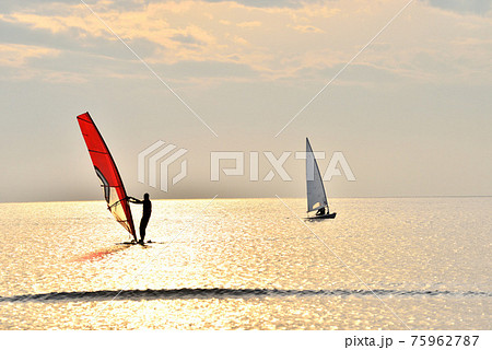 夕刻の材木座海岸に浮かび上がるウインドサーフィンとヨット 75962787