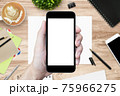 Hand holding smartphone with blank mock-up screen over the wood desk. 75966275