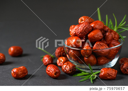 Dried Jujube, Chinese dried red date fruit with rosemary leaf in glass cup on black background, Dried Jujube, Chinese dried red date fruit with rosemary leaf in glass cup on black background, 75970657