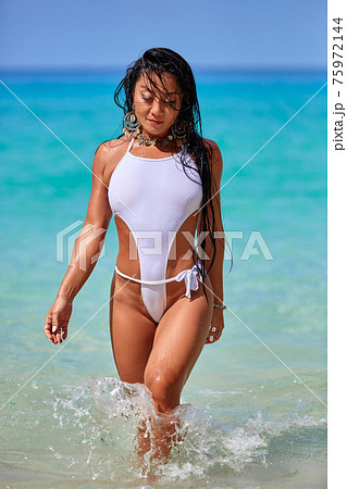 Sexy girl in a white swimsuit walking at the tropical beach Sexy girl in a white swimsuit walking at the tropical beach 75972144