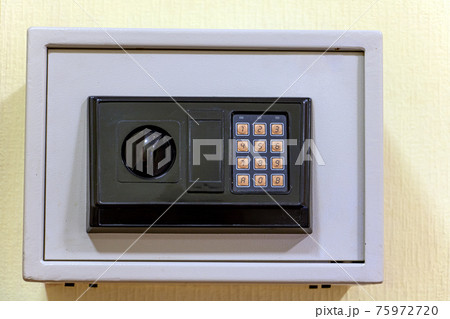 A small safe with a dial is mounted on the wall. 75972720