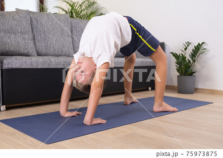Blond boy goes in for sports on yoga mat. Child physical activity at home. Sport healthy lifestyle active leisure Blond boy goes in for sports on yoga mat. Child physical activity at home. Sport healthy lifestyle active leisure 75973875