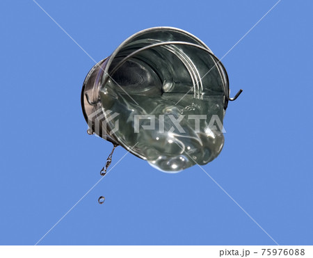 A falling buckets splashes water, on a background of blue sky. A falling buckets splashes water, on a background of blue sky. 75976088