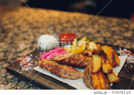 grilled seiki on a wooden board with potato sauce and vegetables. 75976110