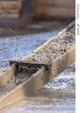Raking concrete. Concrete for parking lot construction. Thick concrete pouring down. Raking concrete. Concrete for parking lot construction. Thick concrete pouring down. 75979132