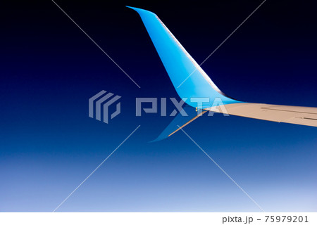 Airplane wing. Blue wing tip of the aircraft against the dark sky. 75979201