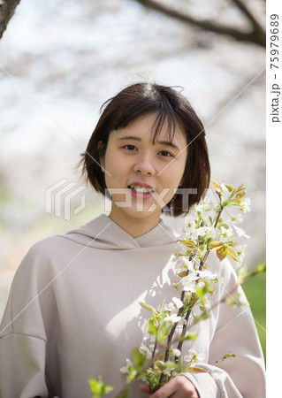 桜の枝をもつ女性ポートレートの写真素材 [75979689] - PIXTA