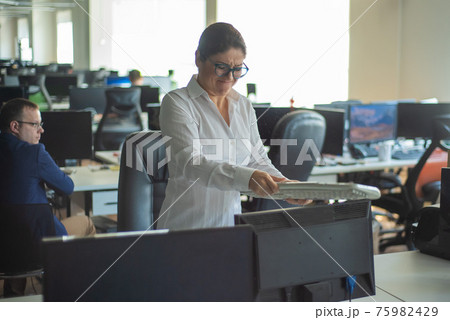 A woman freaks out and gets depressed from a mistake and breaks the keyboard on the monitor. Female manager gets angry and crashes a computer. Office clerk is stressed at work. Unstable psyche. 75982429