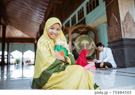 asian girl muslim smiling holding al quran book and learning to read quran with muslim teacher aur ustad 75984505