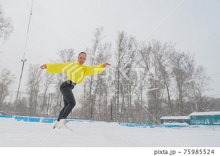 Professional skater on an outdoor ice rink. A woman on knees is preparing a solo program for the competition. 75985524
