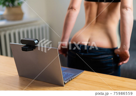 A girl in underwear flirts on an online video connection on a laptop. Woman working as a web cam model A girl in underwear flirts on an online video connection on a laptop. Woman working as a web cam model 75986559