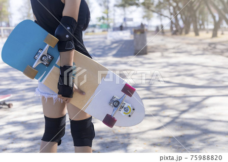 Close up on young women wear protection and hand hold skateboard, surf skate on public skate ramp park background. Free relax skateboard surf skate trendy concept. Fashion portrait of female hands 75988820