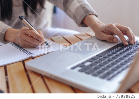 Close up young business woman hands with pen writing notes on paper. female executive sitting at table at home office. Woman's hands writing in spiral notepad placed on wooden table Close up young business woman hands with pen writing notes on paper. female executive sitting at table at home office. Woman's hands writing in spiral notepad placed on wooden table 75988825