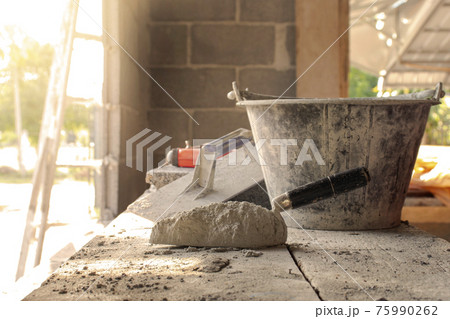 Cement or mortar and trowel with wet cement laid on wood, paper for construction, construction industry working concepts. Cement or mortar and trowel with wet cement laid on wood, paper for construction, construction industry working concepts. 75990262