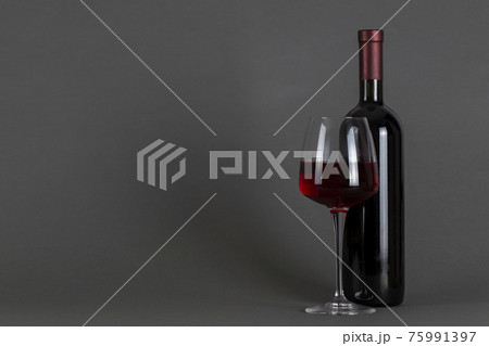 Red wine bottle and glass on a gray background. Wine drinking culture concept. Red wine bottle and glass on a gray background. Wine drinking culture concept. 75991397
