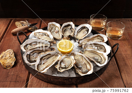 Oysters on a rustic table. A dozen of fresh oysters with lemons and wine Oysters on a rustic table. A dozen of fresh oysters with lemons and wine 75991762