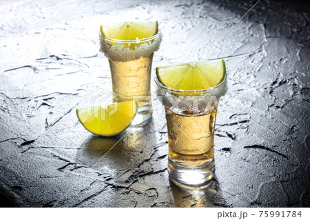 Tequila shots with salted rims and lime slices Tequila shots with salted rims and lime slices 75991784