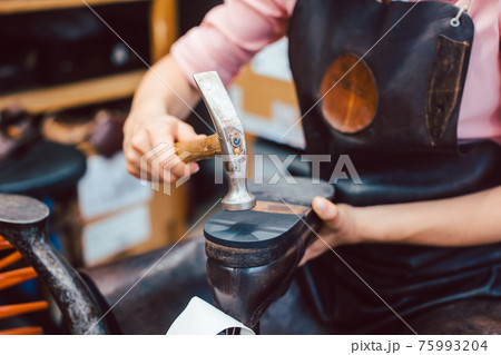Close-up of woman shoemaker repairing some shoes Close-up of woman shoemaker repairing some shoes 75993204