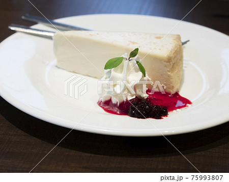 白いお皿に盛り付けられたいちごソースのチーズケーキの写真素材