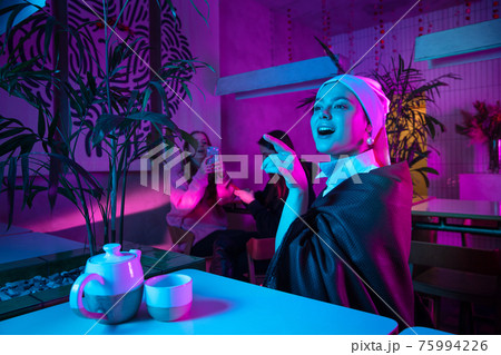 Beautiful girl with a pearl earring taking lunch in modern cafe, restaurant in neon light Beautiful girl with a pearl earring taking lunch in modern cafe, restaurant in neon light 75994226