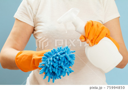 Woman holding a bottle of washing liquid and a rag on a blue background. 75994850