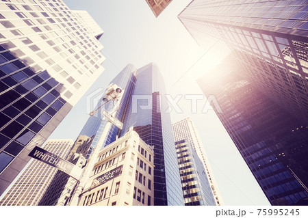 Looking up at New York skyscrapers against the sun, color toned picture, USA. 75995245