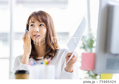 明るい室内でデスクワーク中の女性 75995424