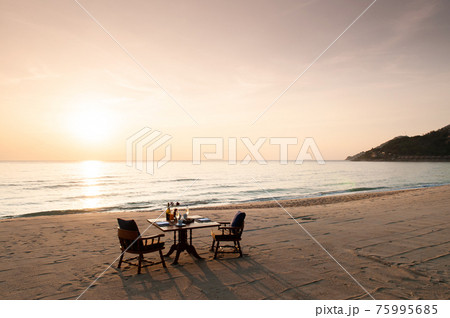 Romantic breakfast on beach. Breakfast table with island sunrise Romantic breakfast on beach. Breakfast table with island sunrise 75995685