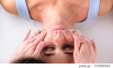 Facial massage beauty treatment. Close up of a young womans face lying on back, getting face lifting 75996004