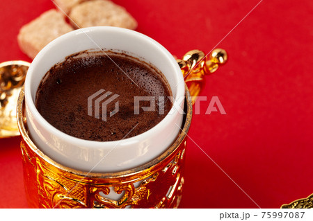 Turkish coffee in a golden oriental cup on red background 75997087